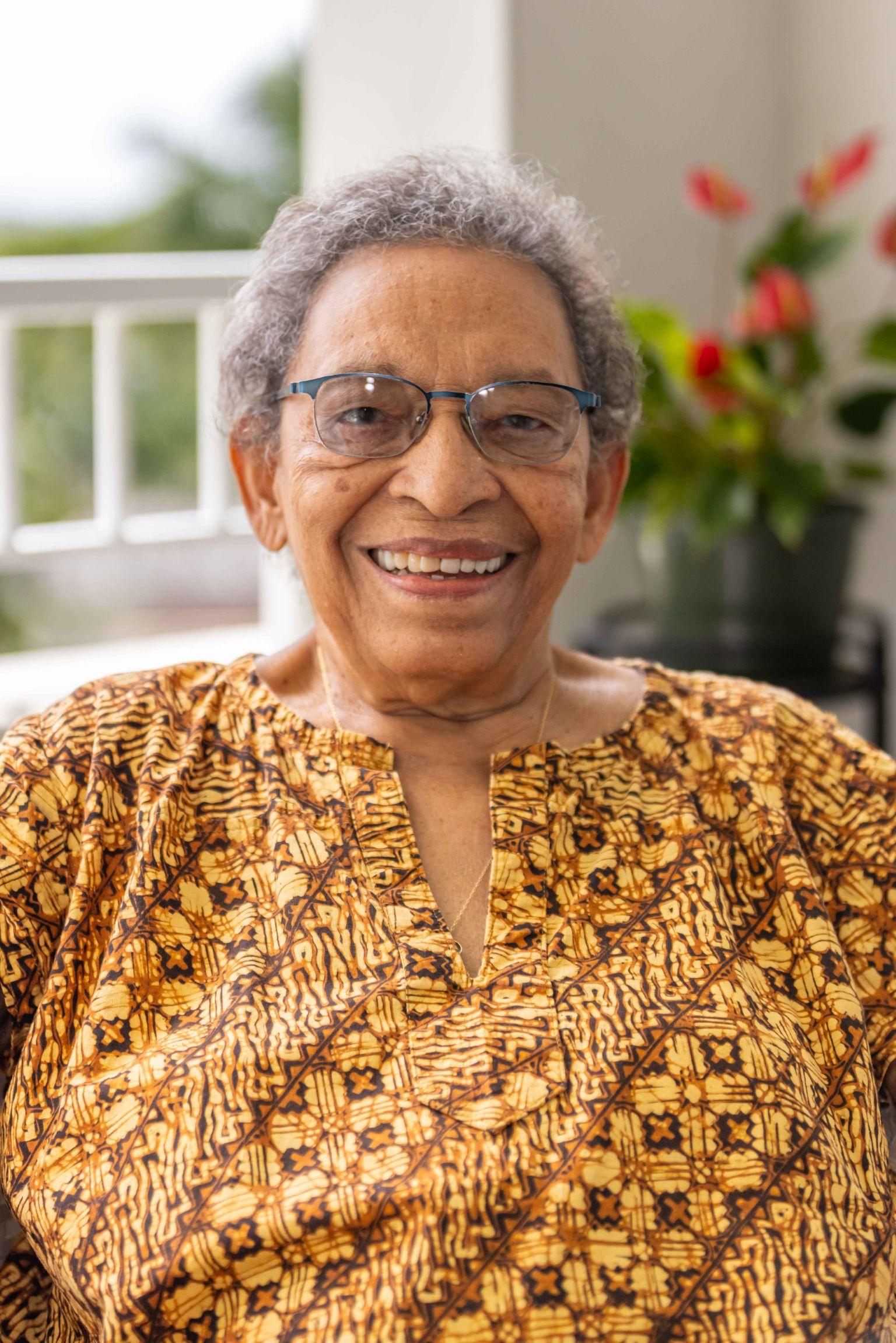 Peggy Antrobus sitting in front of a window, smiling